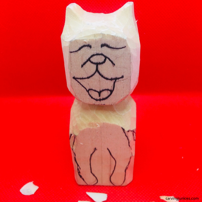 Rounded face and body of cat carving