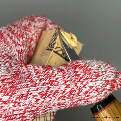 Removing wood with a knife on top corner to carve a cross