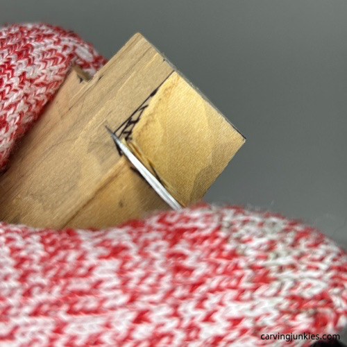 Using knife to make a stop cut on the top of a cross carved from wood