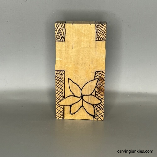 Front guidelines on wood to carve a pocket cross with a flower on it
