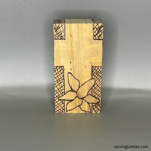 Back guidelines with flower sketched on wood block to carve a cross