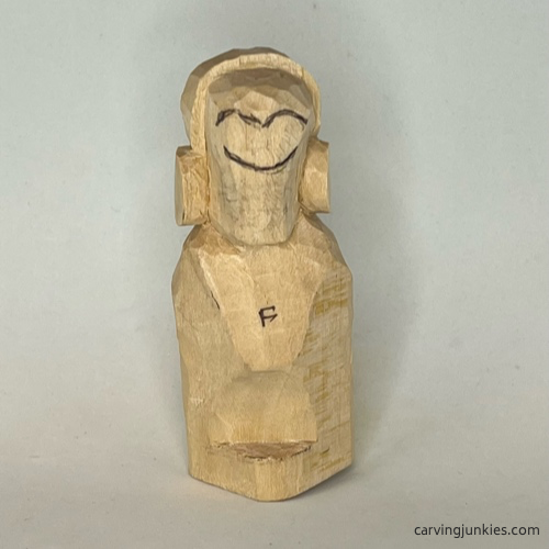 Facial details are sketched on earworm caricature carving