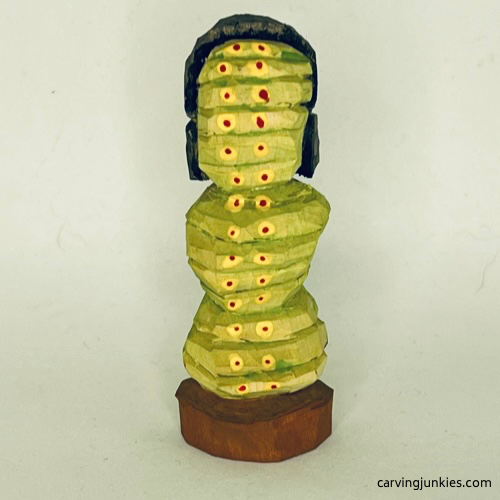 Back view of painted earworm caricature carving