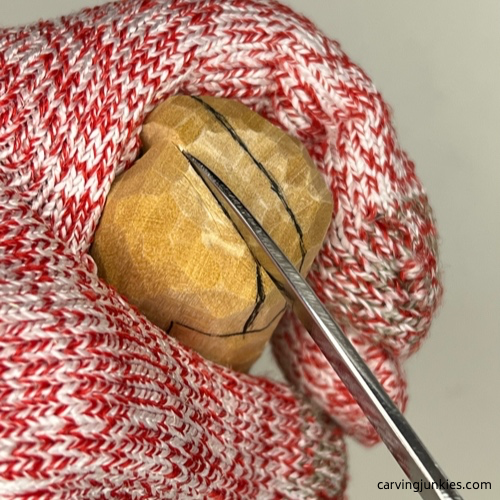 Making a stop cut on top of earworm caricature carving