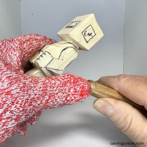 Using knife to separate arms on screw-up fairy wood caricature Carving the arms of screw-up fairy wood caricature