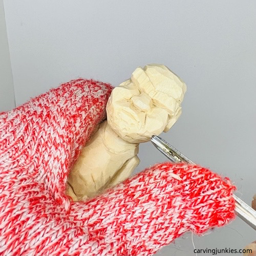 Using gouge to cut a beard on screw-up wood fairy caricature Carving the beard on the screw-up wood fairy caricature