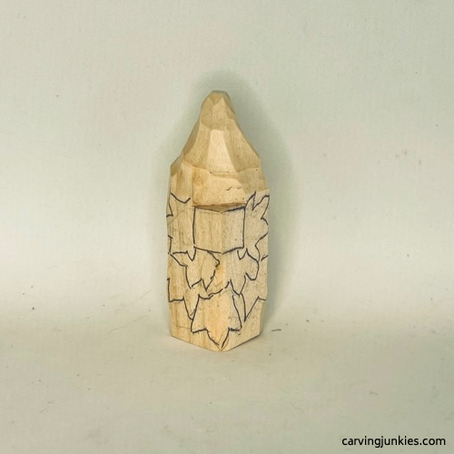 Leaves are sketched on wood carved autumn gnome Details are sketched on fall gnome wood carving