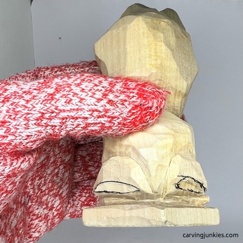 Refining hind legs on wooden frog carving