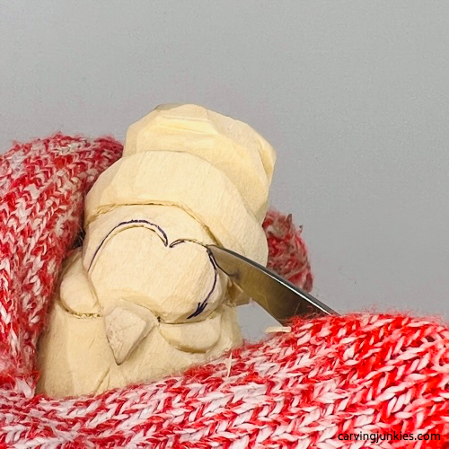 Outlining eyes with knife on carved wood penguin