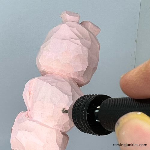 Drilling hole for tail on wood carved pig