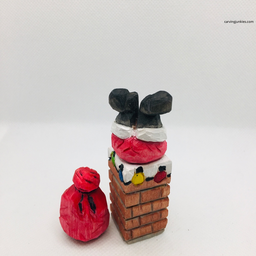 Back view of painted wood carved Santa stuck in the chimney