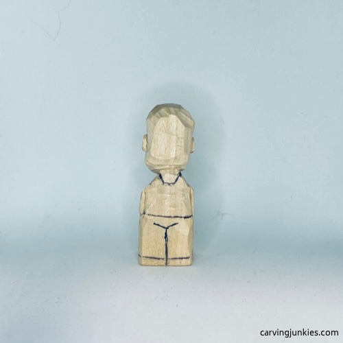 Clothes are sketched on back of tiny wood carving man