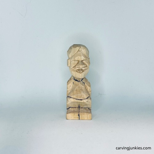 Clothes are sketched on front of tiny wood carving man