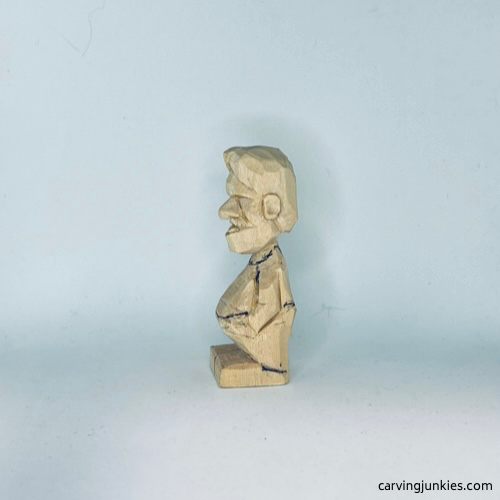 Clothes are sketched on left side of tiny wood carving man