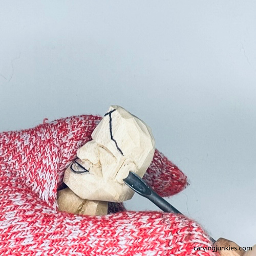 Using gouge on ear on tiny wood carving man