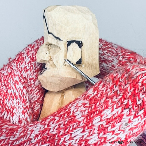 Ears are marked for removal on tiny wood carving man