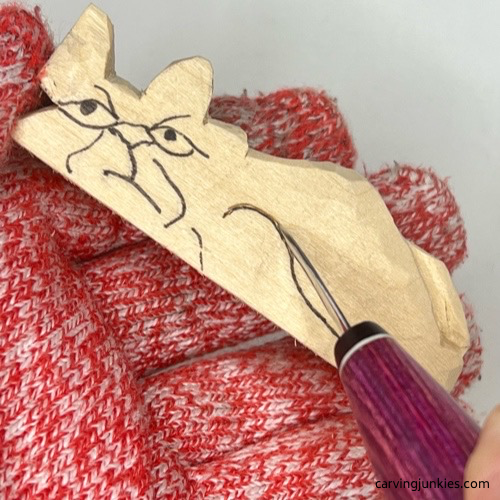 Carving front paw on cat whittling Separating details on the face of whittled cat