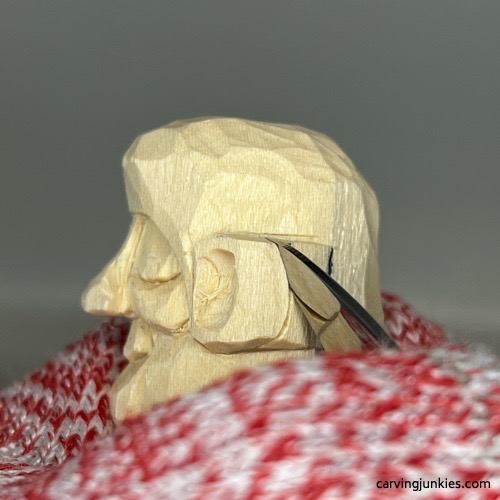 Shaping back of ear on wooden Buddha
