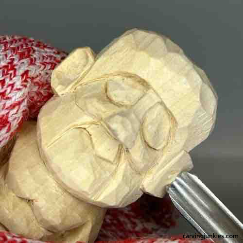 Using U gouge to carve inner ear on wooden Buddha