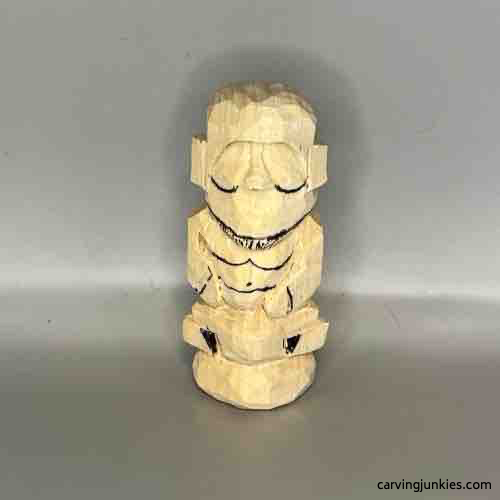 Face details are sketched on wood carved Buddha