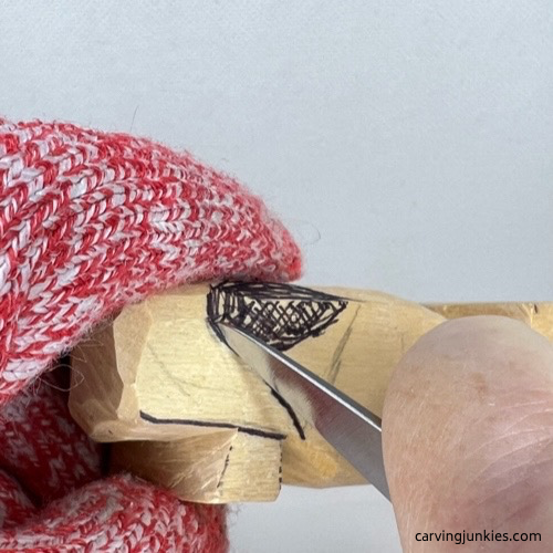 Separating the tail with a knife while carving a wooden alligator
