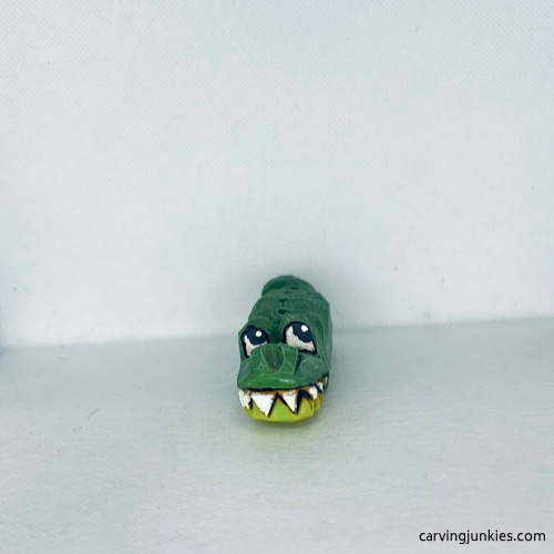 Front view of green painted wood carved alligator with big white teeth and big yes