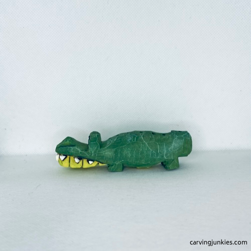 Left view of wood carved alligator with two shades of green paint