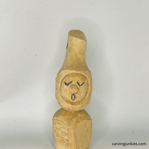 Face details are drawn on wood carved Christmas caroler