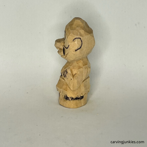 Drawn details on left side of wood carved caveman Left view of details sketched on wood carved caveman