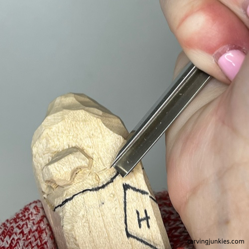Using V-tool to carve mouth on wood carved caveman Carving mouth of wood carved caveman with V tool