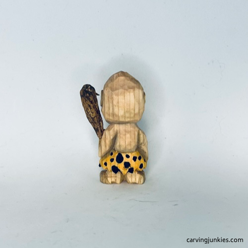 View of painted wood carved caveman from the back Back view of painted wood carved caveman