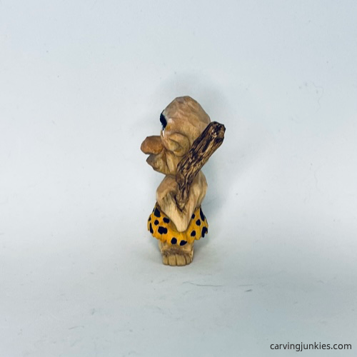 View of painted wood carved caveman from the left side Left view of painted wood carved caveman