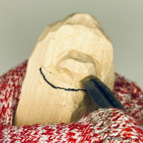 Using U-gouge to carve nostrils on wood carved caveman Carving nostrils on wood carved caveman with a U gouge