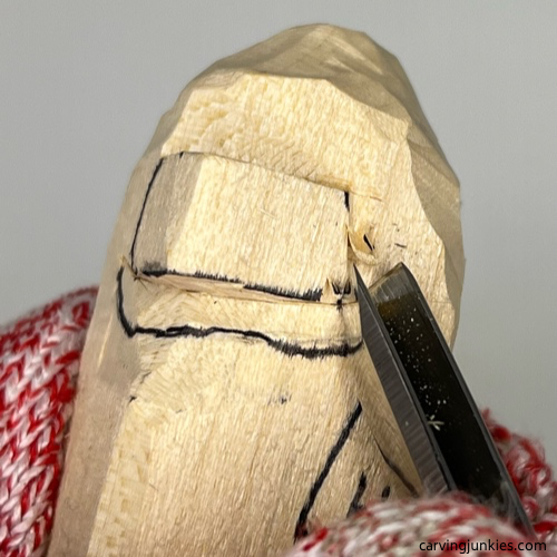 Carving side of nose with V-tool on wood carved caveman Using V tool to carve nose on wood carved caveman