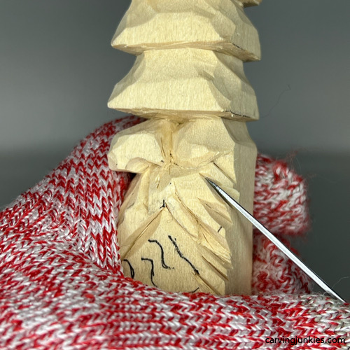 Carving notches on mustache of wood carved Christmas tree gnome