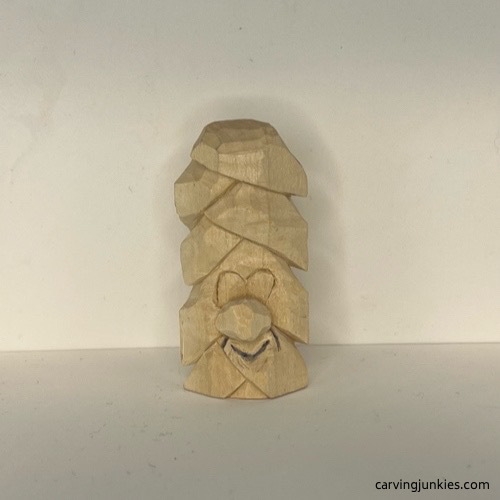 Mouth is drawn on wood carved Christmas tree ornament Smile lines are drawn on wood carved Christmas tree ornament