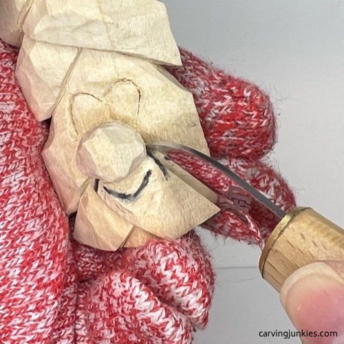 Starting to carve smile lines for wood carved Christmas tree ornament Carving smile lines on wood carved Christmas tree ornament