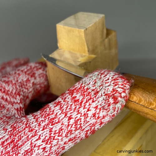 Refining top sections of a wooden cross with a knife