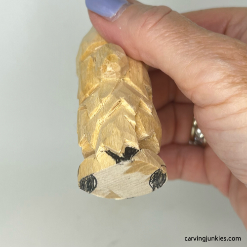 Wood for shoes is marked for removal on wood carved autumn gnome Marking wood for removal on fall gnome wood carving