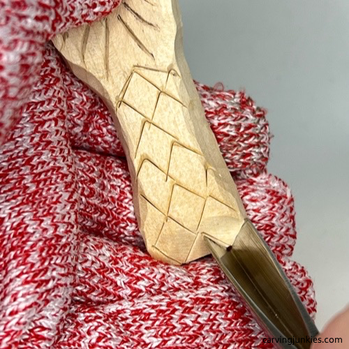 Using V-tool to carve scales on wood carved mermaid