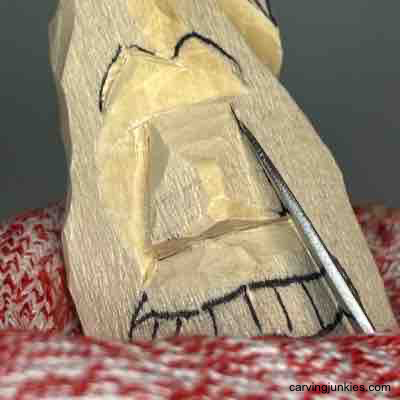 Carving nose sides on wood carved pear caricature