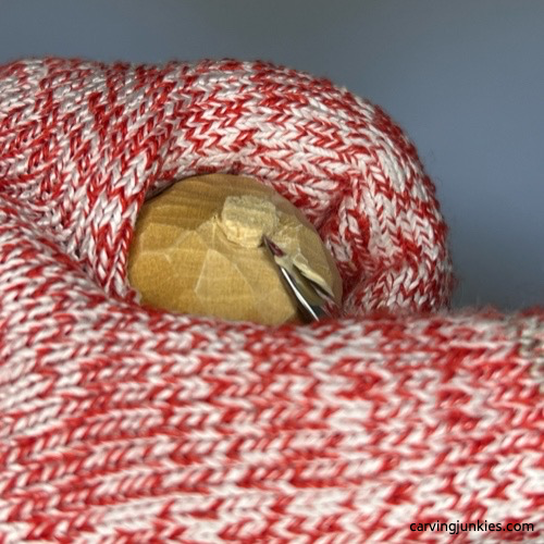 Using knife to carve pom-pom on wood carved snowman