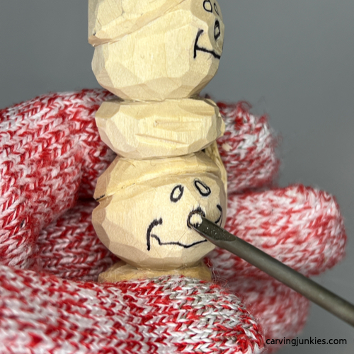Carving nose on wood carved snowman
