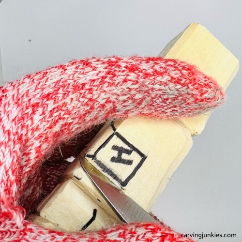 Making stop cut on hand of carved wooden knight