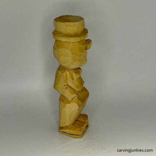 Side view of unpainted little man caricature carving